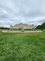 Obraz premium Front side of Belvedere castle with green grass and circle pond in cloudy day portrait