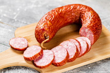 Cut into pieces of salami on a wooden cutting board. 