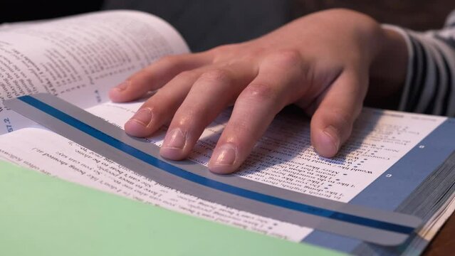 Reading tools for dyslexia. Child doing homework, reading book using colorful ruler overlay strips. Education, learning disability, reading difficulties concept