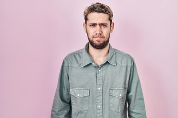 Hispanic man with beard standing over pink background skeptic and nervous, frowning upset because of problem. negative person.