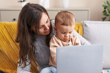 Mother and son using laptop sitting on sofa at home