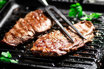 Grilled steak with parsley in a frying pan. 