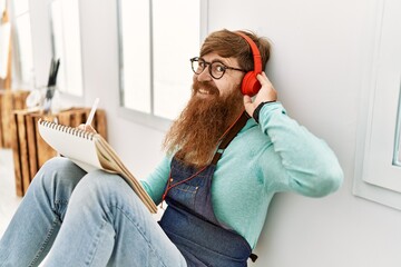 Obraz premium Young redhead man listening to music and drawing at art studio