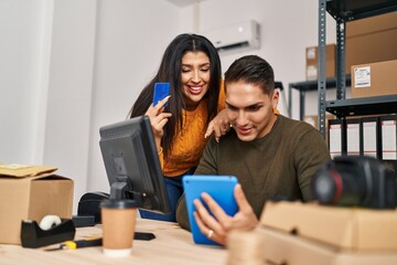 Man and woman ecommerce business workers using touchpad and credit card at ecommerce office