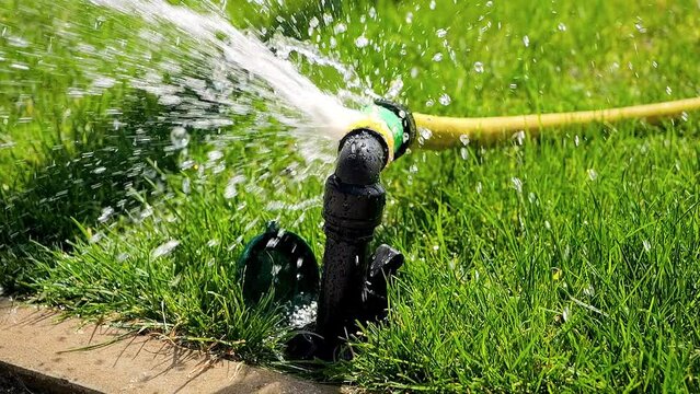 Slow motion of water stream splashing through leaking hose pipe. Water waste, garden equipment, gardening