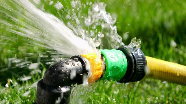 Slow motion of water leaking and flowing through pipe and gardening hose connection. Water waste, equipment, gardening