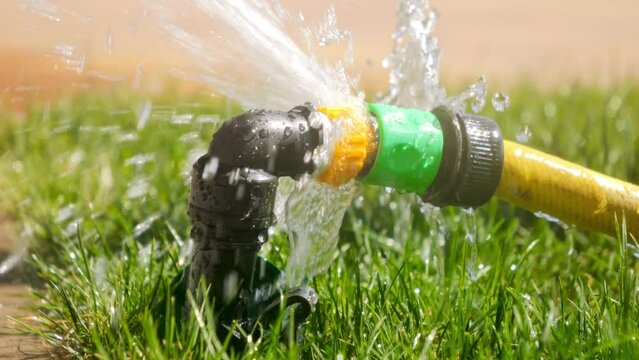 Slow motion of water droplet leaking through damaged garden hose and pipe. Water waste, garden equipment, gardening