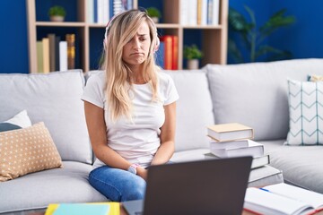 Obraz premium Young blonde woman studying using computer laptop at home depressed and worry for distress, crying angry and afraid. sad expression.