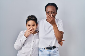 Young mother and son standing together over white background laughing and embarrassed giggle...