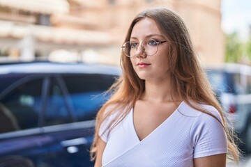 Young blonde woman looking to the side with serious expression at street