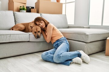 Obraz premium Young caucasian woman sleeping sitting on floor with dog at home