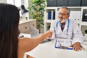 Fototapeta premium Senior grey-haired man doctor and patient shake hands at clinic