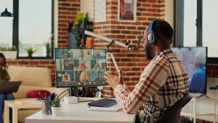 Male manager attending corporate videocall meeting on computer with webcam, talking to people on videoconference. Using remote teleconference call to chat on internet, work from home.