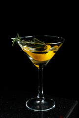 Transparent alcohol cocktail Smoky Martini with lemon zest and rosemary on black background.
