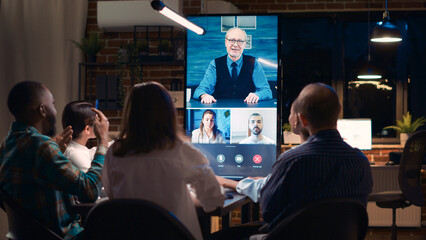 Employees greeting elderly executive in videocall, waving hi, colleagues videoconference...
