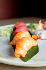 four nigiri sushi with salmon and tuna served on fresh green banana leaf on black background with japanese sign © leo