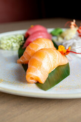 four nigiri sushi with salmon and tuna served on fresh green banana leaf on black background with japanese sign © leo