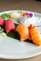 four nigiri sushi with salmon and tuna served on fresh green banana leaf on black background with japanese sign © leo