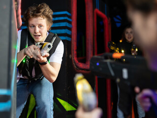 Fototapeta na wymiar Portrait of young man with laser gun having fun with family on laser tag arena