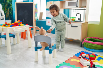 Adorable hispanic toddler playing with play kitchen and toys at kindergarten