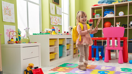 Adorable blonde girl smiling confident playing maraca at kindergarten