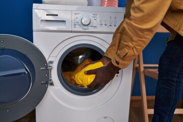 Young african american man washing clothes at laundry room