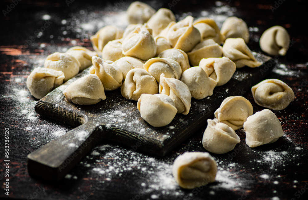 Poster raw homemade dumplings on a flour cutting board.