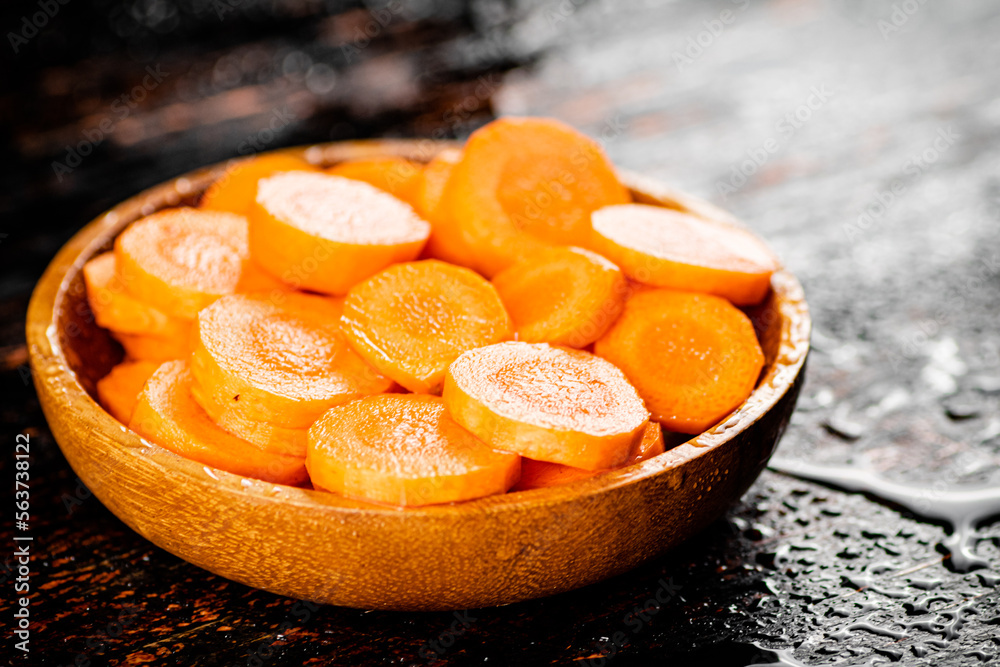 Canvas Prints Round pieces of fresh carrots on a wooden plate. 