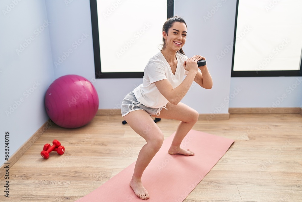 Sticker Young beautiful hispanic woman smiling confident training legs exercise at sport center