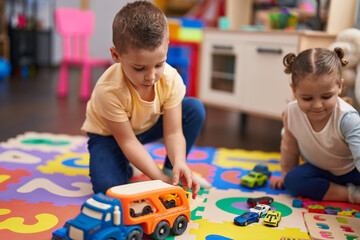 Two kids playing with cars toy and maths game sitting on floor at kindergarten