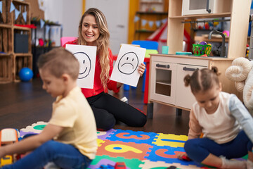 Teacher with boy and girl sitting on table having emotion therapy at kindergarten
