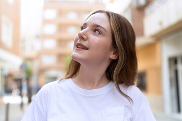 Young caucasian woman smiling confident looking to the sky at street