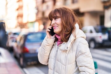 Middle age woman smiling confident talking on the smartphone at street