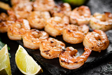 Grilled shrimp on a stone board with pieces of lime. 