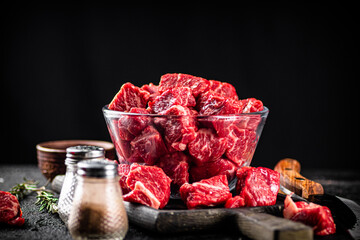 Raw beef tenderloin in a glass bowl with spices. 