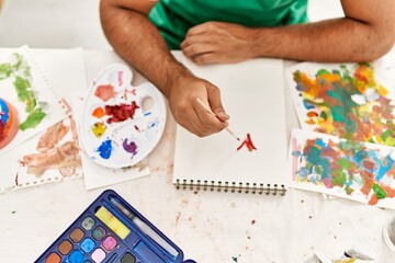 Young hispanic man drawing on notebook at art studio