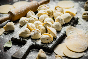 Fototapeta na wymiar Homemade dumplings on a cutting board with flour. 