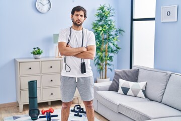 Handsome latin man wearing sportswear at home skeptic and nervous, disapproving expression on face...
