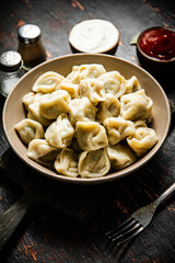 Dumplings in a plate on a cutting board with tomato sauce and sour cream. 