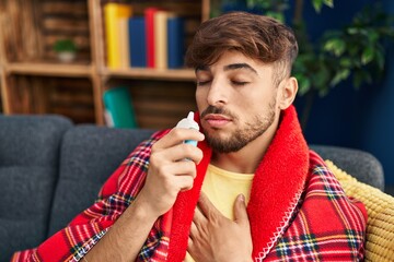 Young arab man using nasal machine sitting on sofa at home