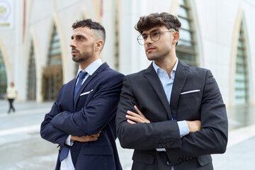 Two hispanic men business workers standing with arms crossed gesture at street