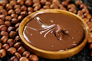Hazelnut butter on a wooden plate with peeled hazelnuts.