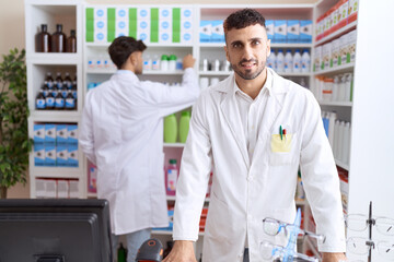 Two hispanic men pharmacists smiling confident working at pharmacy