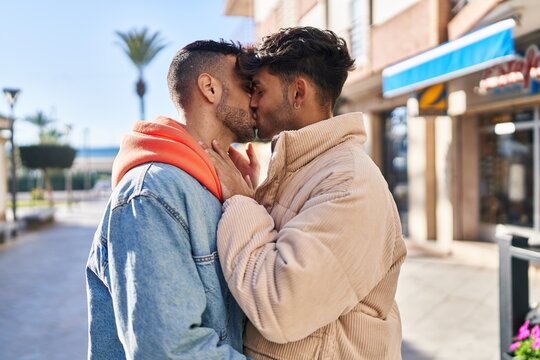 Two man couple hugging each other and kissing at street