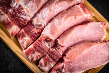Raw pork sliced on a wooden cutting board. 