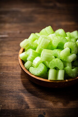 A wooden plate with a piece of celery. 