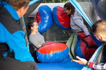 Happy female friends fighting by big stuffed boxing gloves at outdoor amusement playground