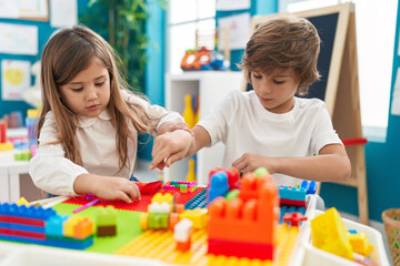 Fototapeta premium Brother and sister playing with construction blocks sitting on table at kindergarten