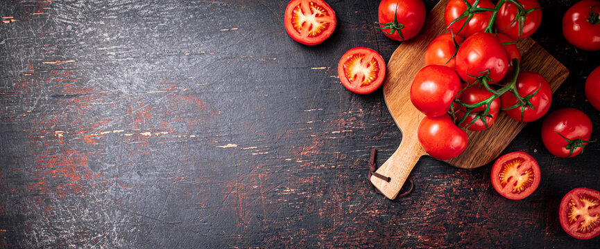 Fresh tomatoes on a wooden cutting board. 