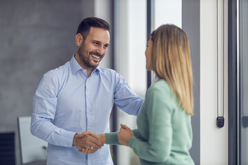Two business people shaking hands while sitting at the working place
